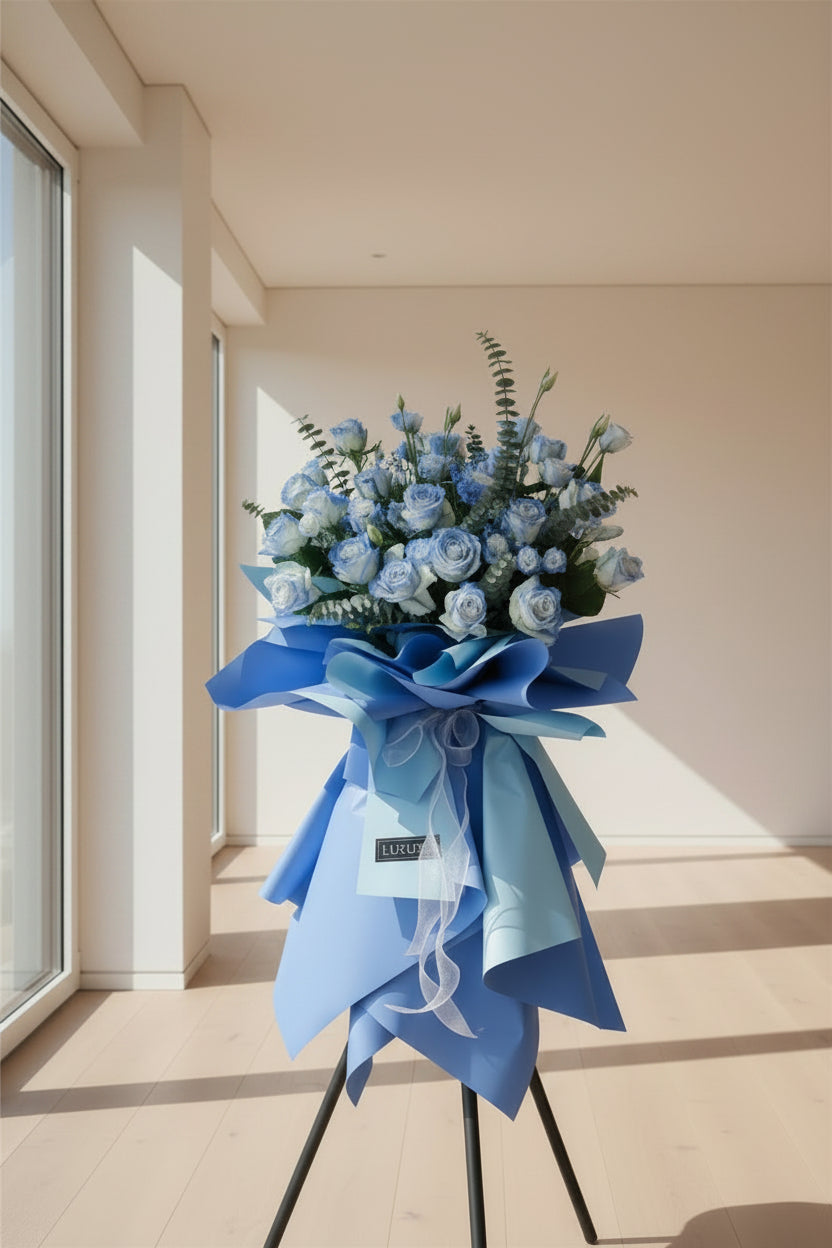 Two large blue and white artificial flower stands with blue ribbon wrapping, displayed in a shop setting.